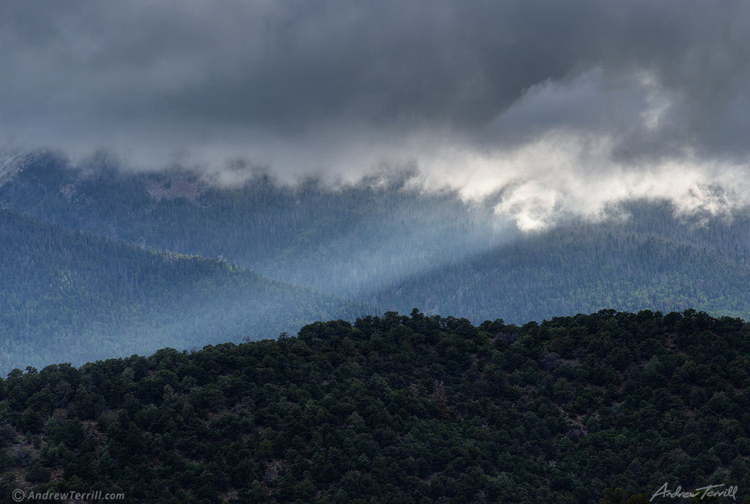 sunbeam shining over forest and mountains under storm cloud coloraod