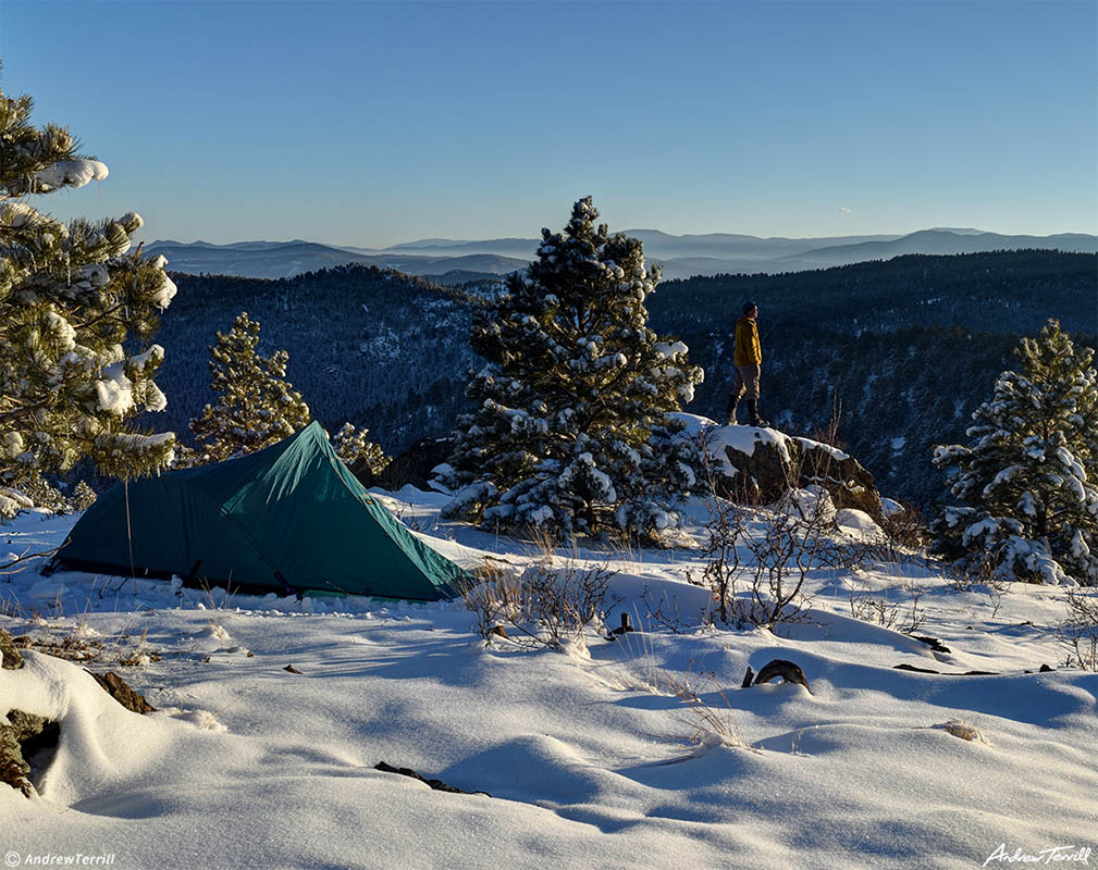 winter camp in snow in front range foothills colorado with tent and lone figure camping