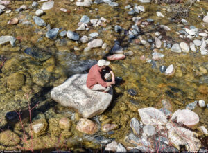 andrew terrill sitting on rock in creek