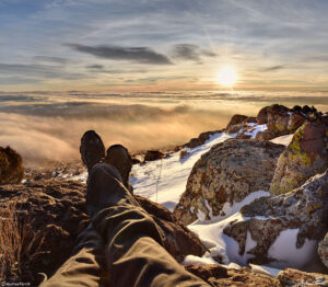 stretching out feet towards sunrise above the clouds