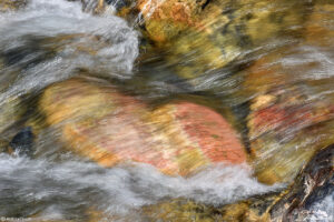 water rushing over colorful river rocks