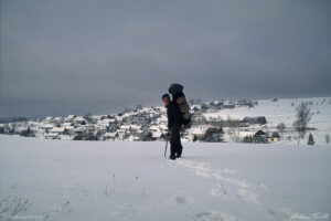 hiker andrew terrill approaching village in winter landscape austria