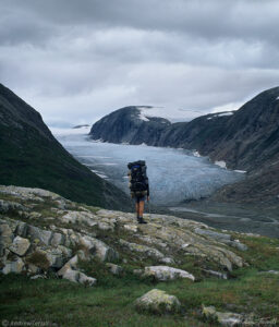 hiker on rocks near glacier in svartisen wilderness norway