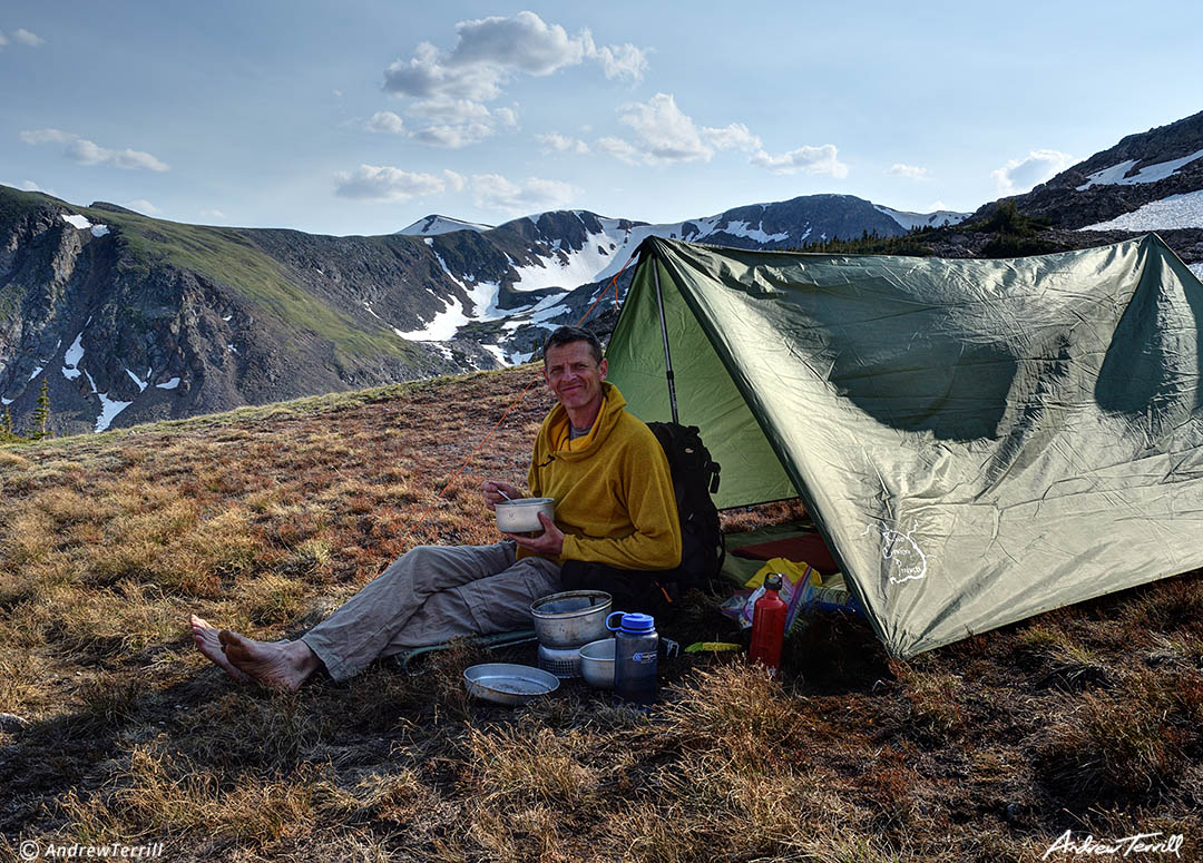 andrew terrill eating dinner in wilderness camp with tarp tent