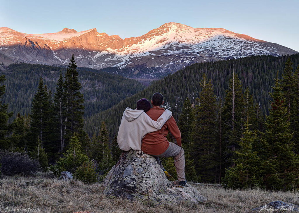 watching the mountain view in colorado at sunset alpenglow two figures arm over shoulder