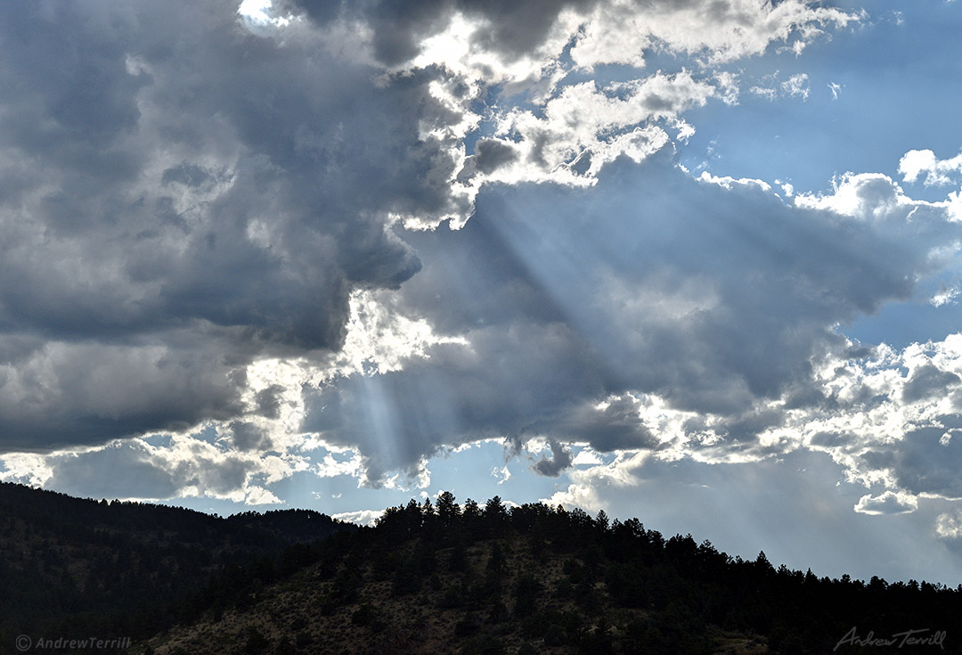 sunbeams and clouds over colorado foothills and forests