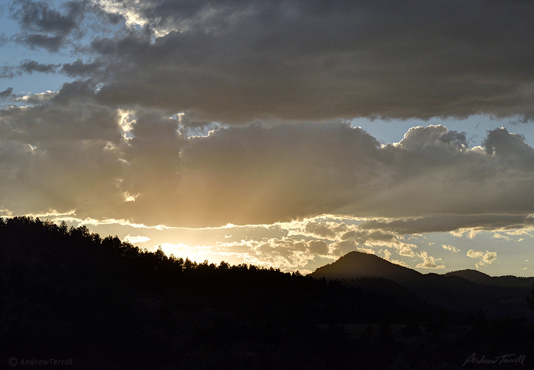 sunlight bursting over forest and mountain ridge