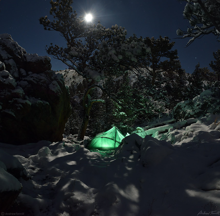 glowing tent in snowy mountains beneath moon