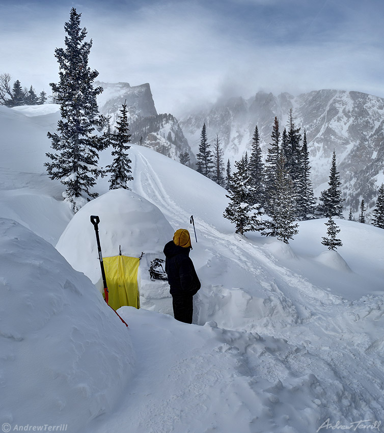 standing outside igloo in snow covered mountains